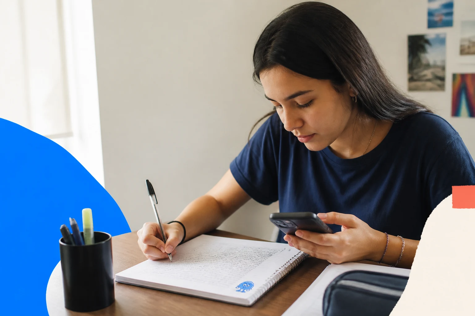 Estudante escreve uma redação no caderno e acompanha a correção no celular